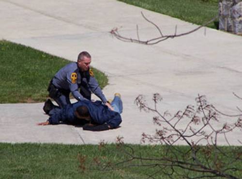 En una imagen provista por la televisora WSLS, un hombre no identificado es detenido por un guardia del Tech en el campus de Blacksburg